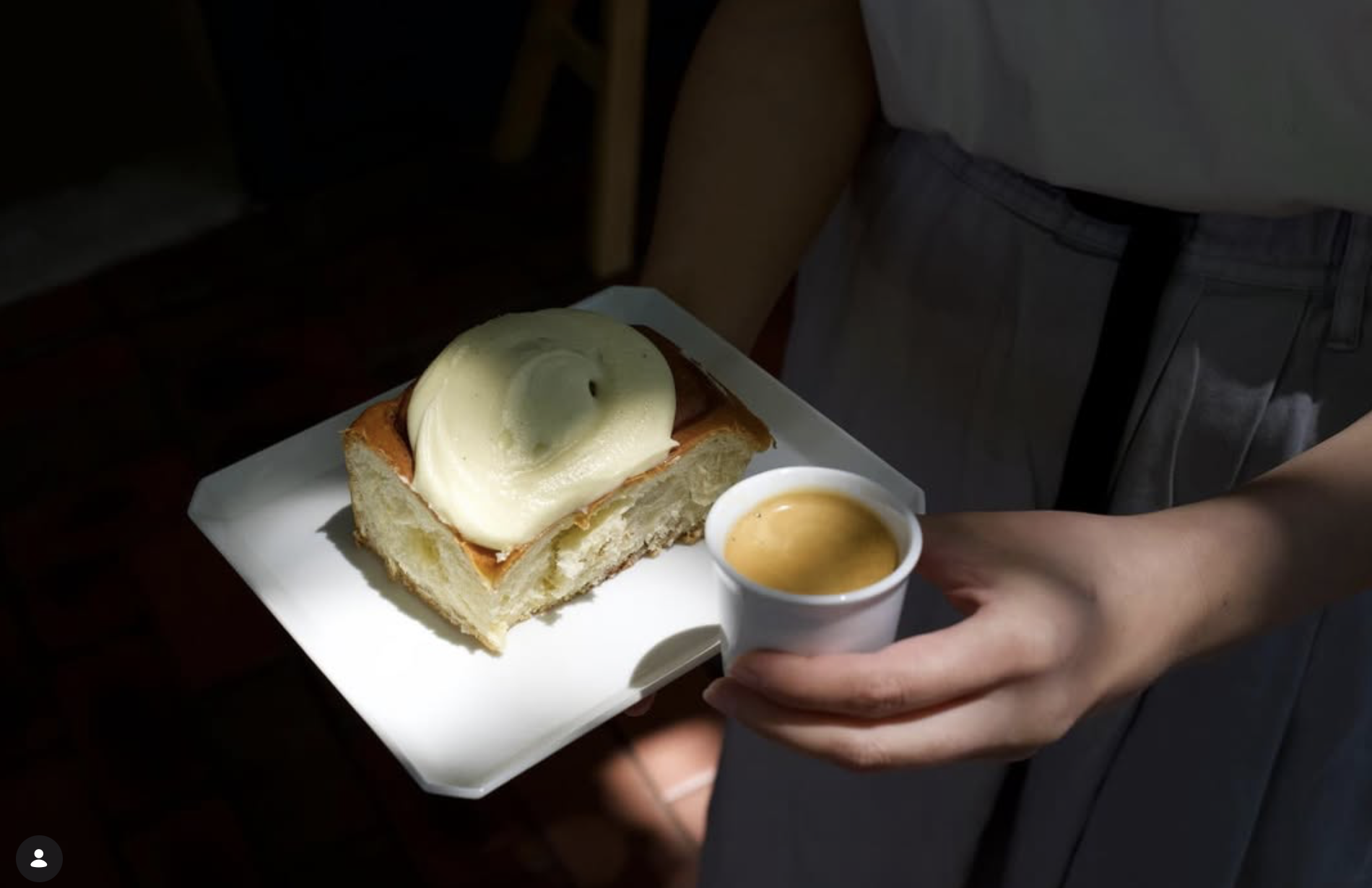 Fresh pastry and espresso served on a tray, warm hands in an apron